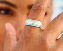 model holding her hand up to camera wearing trans pride ring