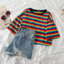 Folded Shirt with striped colors laying next to a pair of blue jean shorts and sunglasses