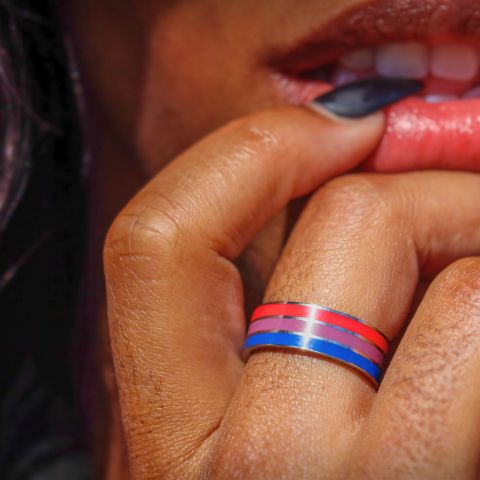 bi pride ring on girls middle finger holding her hand to her lips