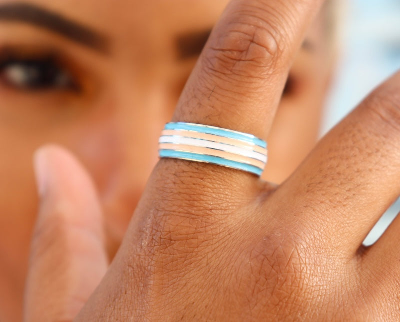 model holding her hand up to camera wearing trans pride ring